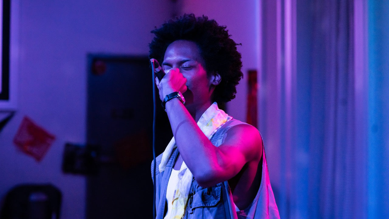 Person singing into a microphone with a blue and purple light effect